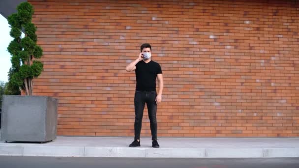 Jonge man in masker praten aan de telefoon — Stockvideo