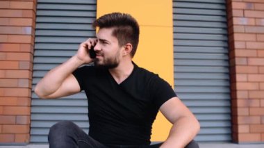 Toplu taşımayı beklerken telefonda konuşan karizmatik bir gencin portresi..