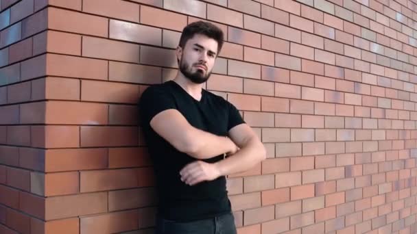Stolzer junger Mann lehnt an Ziegelmauer — Stockvideo