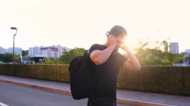 Sırtında halıyla sokakta yürüyen ve müzik dinleyen mutlu genç bir adam..