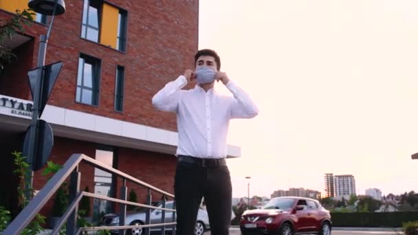 Blanc d'âge moyen bel homme en lunettes de soleil prenant un masque médical dans la rue de la ville. Extérieur. — Video