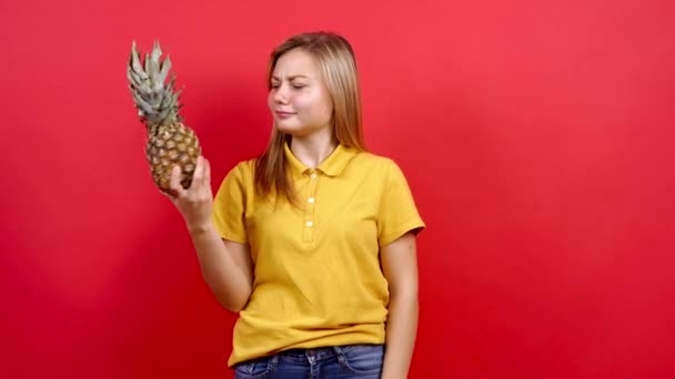 Linda y ligeramente gorda chica en una camiseta amarilla que mantiene la piña fresca en su mano, — Vídeos de Stock