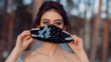 Yüzüne mavi kelebeklerine dikilmiş siyah bir maske takan nazik bir genç kadının portresi..