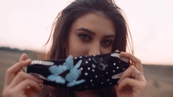 Ett porträtt av en ung flicka som håller en svart mask med fjärilar i handen.. — Stockvideo
