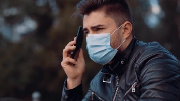 Een jongeman met een masker op zijn gezicht krijgt een telefoontje. Hij is kalm en spreekt langzaam. — Stockvideo
