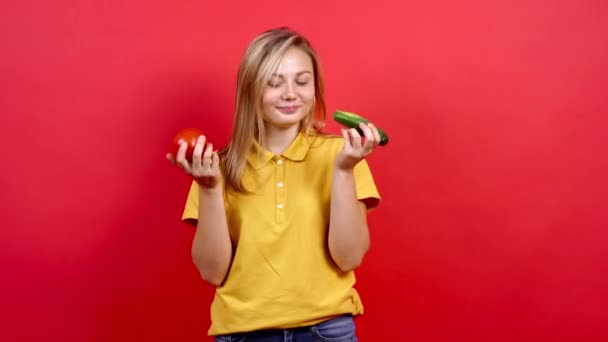 Słodka i lekko gruba dziewczyna w żółtym T-shircie, ma ogórek i świeży pomidor w ręku, — Wideo stockowe