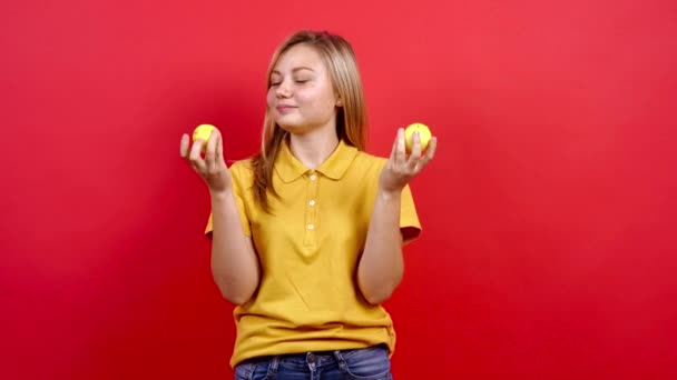 Schattig en licht dik meisje in een geel T-shirt speelt en ruikt twee citroenen, — Stockvideo
