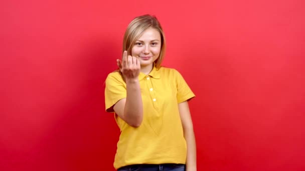 Vacker vit kvinna i gul T-shirt och långt blont hår, står på en röd bakgrund, — Stockvideo