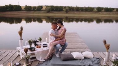 Romantik çift. Genç adam kız arkadaşını ışıklarla dolu bir güvertede kollarında tutuyor..