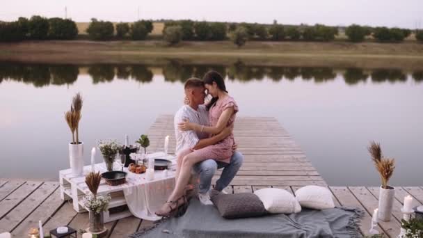Romantisch stel. Jongeman houdt zijn vriendin in zijn armen op een dek vol lichten. — Stockvideo