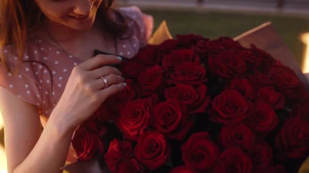 Plan met een jonge vrouw verlovingsring, terwijl ze een boeket rozen in haar armen houdt. — Stockvideo