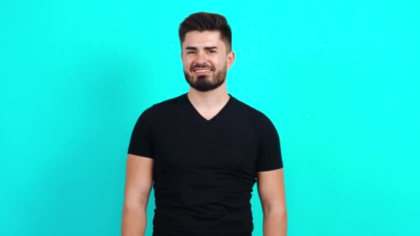 Young Caucasian guy in a black T-shirt looking at the camera with a charming smile. — Stock Video