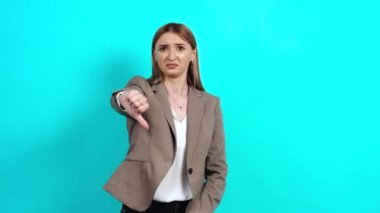 Tatminsiz bir kadın, üzgün, iş elbisesi içinde, el hareketini başparmağı aşağıda gösteriyor.