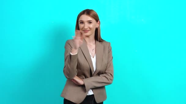 Γυναίκα με καστανά μαλλιά, φιλική, θετική, σε ένα κομψό κοστούμι, κουνώντας το χέρι της — Αρχείο Βίντεο