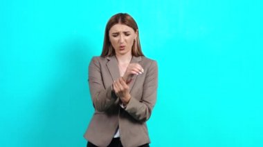 Hüsrana uğramış, takım elbiseli genç bir kadın, bileğine masaj yapıyor, acı çekiyor.