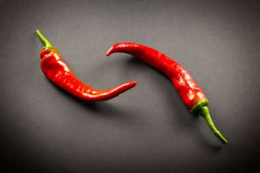  Koyu arkaplanda iki parça kırmızı biber.