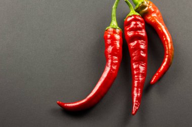 Siyah arka planda üç kırmızı biber.