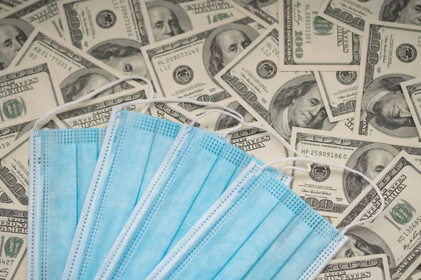 Máscara azul descartável no fundo de notas de cem dólares, dólares em dinheiro — Fotografia de Stock