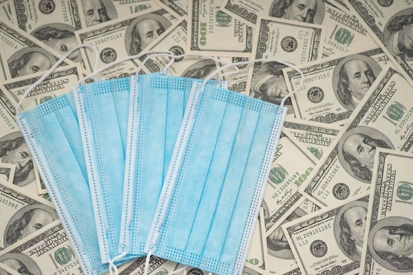 Disposable blue masks on the background of hundred dollar bills. Business and finance