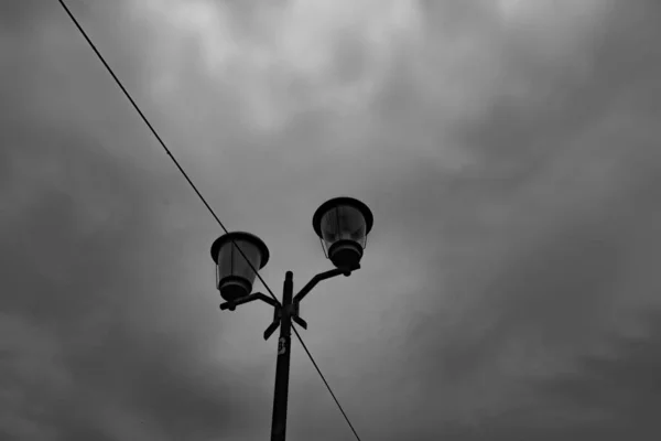 Lampadaire lumineux à l'ancienne placé contre un ciel nuageux sombre. — Photo