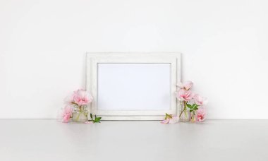 Yatay ahşap çerçeve mockup, pembe çiçekler, beyaz arka plan ile küçük şişeleri