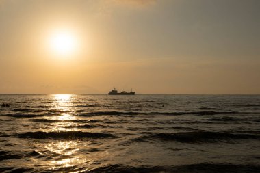 Römorkör gün batımında tankeri denize çekiyor.