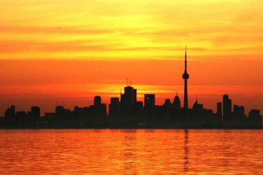 Torontos 'un silueti gün doğumunda gökyüzünde beliriyor. Bu fotoğraf Toronto 'nun ikonik CN kulesini ve şehrin birçok gökdelenini altın arka planda gösteriyor..