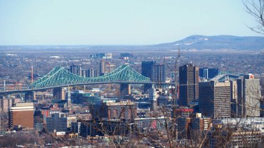 Soğuk bir kış gününde Montreal siluetine karşı yeşil bir Jacques Cartier Köprüsü. Ufuk çizgisi şehir genelinde yüksek gökdelenlerle dolu..