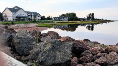 Alberton, PEI 'nin güneyindeki Northport İskelesi' nde sakin bir yaz akşamı, doğu kıyısı sahil kulübelerinin güzel bir görüntüsünü yansıtan Atlantik Okyanusu suları yaratıyor..