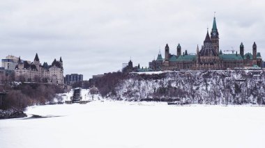 Parliament Hill 'in Ottawa, Ontario, Kanada' daki manzarası. Kanada 'daki Parlamento Binası soğuk bir kış gününde Parliament Hill' de dimdik ayakta duruyor. Ottawa Nehri hala kışın köpekleri tarafından donduruluyor..
