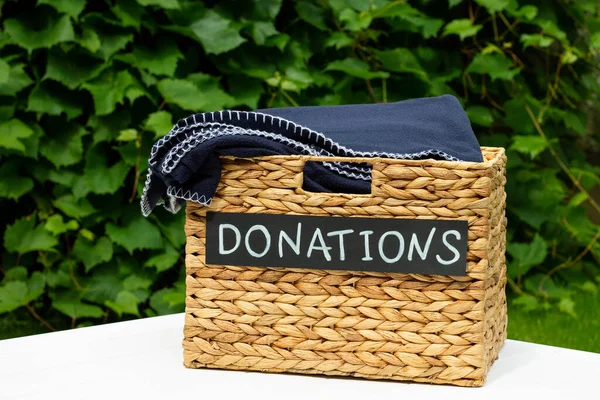 Donation box for clothing donations on a greenery background. Charity and donation concept, copy space.