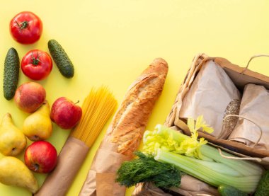 Taze organik ekmek, sebze, yeşillik ve meyve, mısır gevreği ve sarı arka planda makarna. Ekolojik tarım gıda konsepti. Üst Manzara. Düz yatıyordu