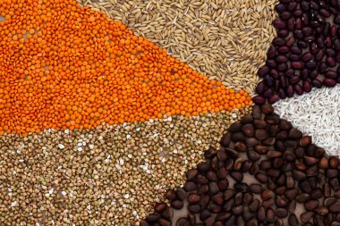 Üçgenlerin arka planında çeşitli tahıllar ve fındıklar var.