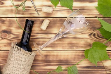 Şarap kadehi, tirbuşon, mantar, şarap şişesi, yakılmış ahşap arka planda dedikodu. Üst görünüm, alanı kopyala