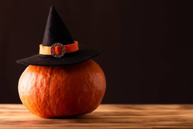 Kahverengi arka planda bir cadı şapkası içinde cadılar bayramı turuncu kabağı, kopyalama alanı.