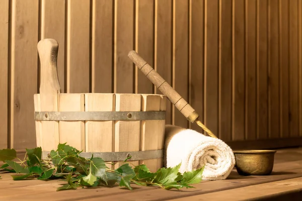 Wooden bucket, birch broom, towel and ladle in the steam room of the sauna, copy space