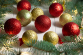 Zelené větve vánočního stromku s LED žárovkami, girlandem a lesklými koulemi na bílém dřevěném pozadí. Veselé Vánoce a šťastný nový rok koncept