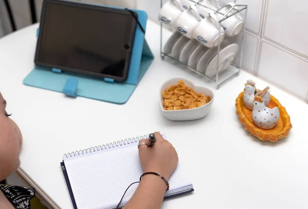 Girl studying in the kitchen with technology tools