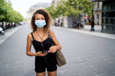 Koronavirüsten korumak için maske takan genç bir kadın sokakta yürüyor.