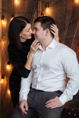 Aşıkların mutlu çift pencere kenarında oturmak. Noel atmosferi evde. Genç ailenin bir arada. Ön plan bokeh Garland ışıklar