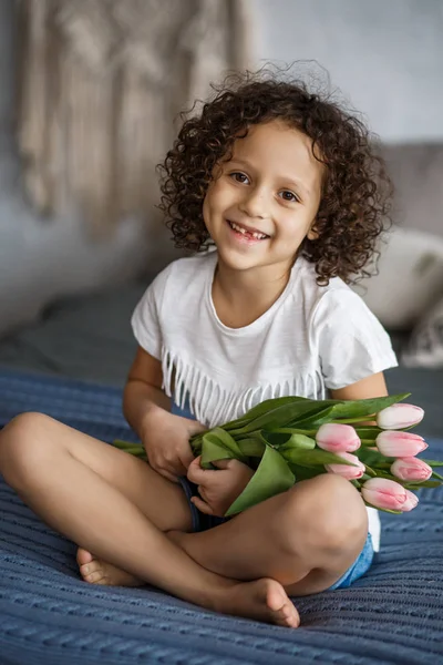 Happy mother\'s day, daughter gives a bouquet of tulips. African-American girl with a smile without teeth.