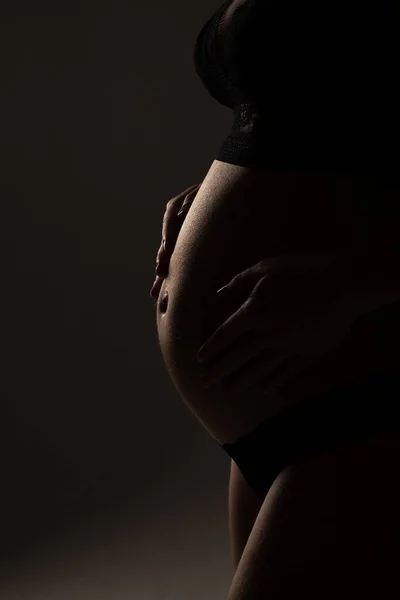 Close Up of pregnant woman's belly, side view. silhouette of Pregnant woman on a black background — Stock Photo, Image