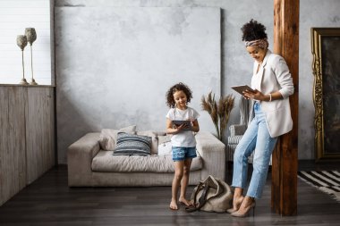 Mutlu sevgi dolu aile. Genç anne ve kızı kızı çocuk odası oynamak. Komik anne ve güzel çocuk tablet ile eğleniyor musun.