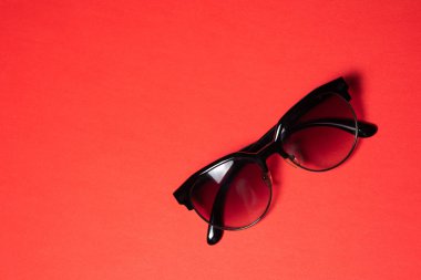 Güneş gözlüğü kırmızı arka planda yalan, yakın çekim.