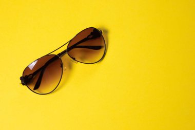 Güneş gözlüğü sarı bir arka planda yalan, yakın çekim