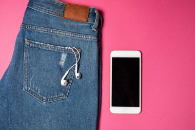 Kopya alanı ile düz arka plan. Rahat kadın kıyafeti, kot pantolon ve kulaklıkların üst görünümü