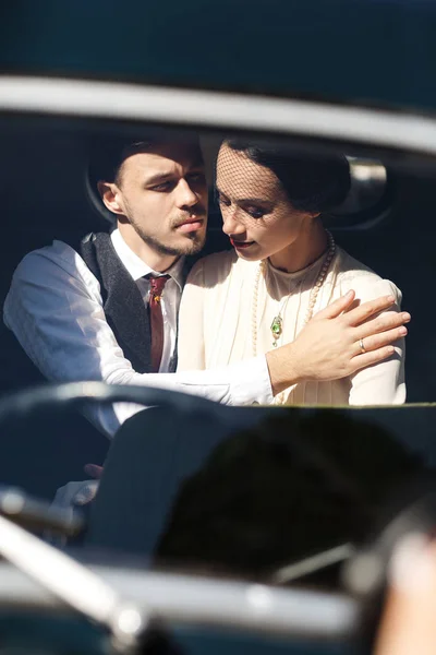 Femme habillée dans un style démodé se trouve dans une voiture rétro avec son homme — Photo