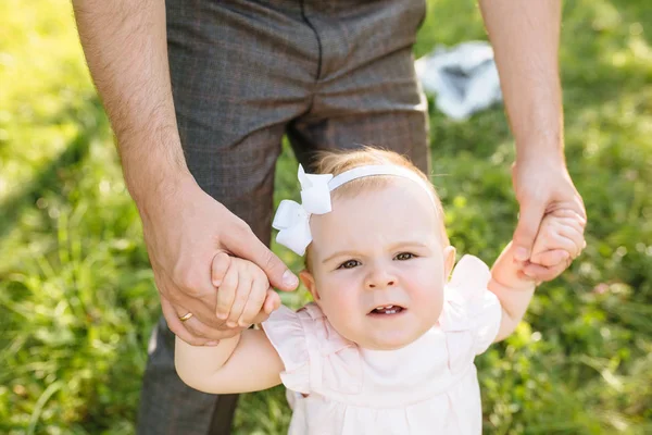 Cute little beautiful girl 6 months walking in the park with parents. — Stock Photo, Image