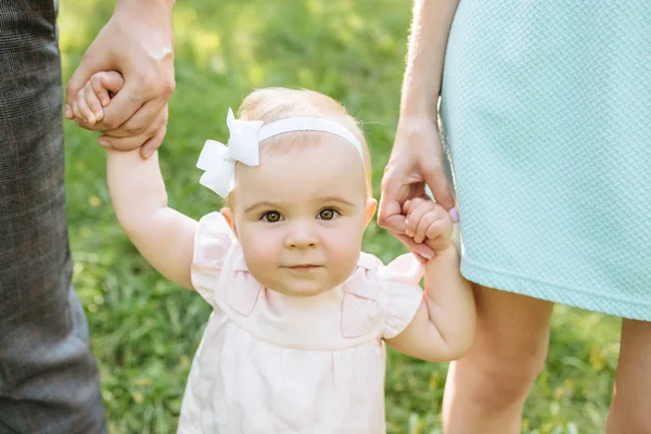 귀여운 작은 아름다운 소녀 6 개월 부모와 함께 공원에서 산책. 로열티 프리 스톡 이미지