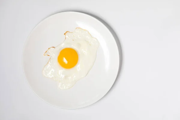 Huevo frito en un plato blanco. Aislado sobre fondo blanco —  Fotos de Stock